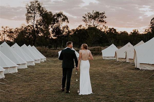 bell tent village set up for wedding guests being viewd by bride and groom
