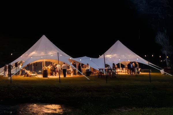 Outdoor event at night under a connecting starshade maquee