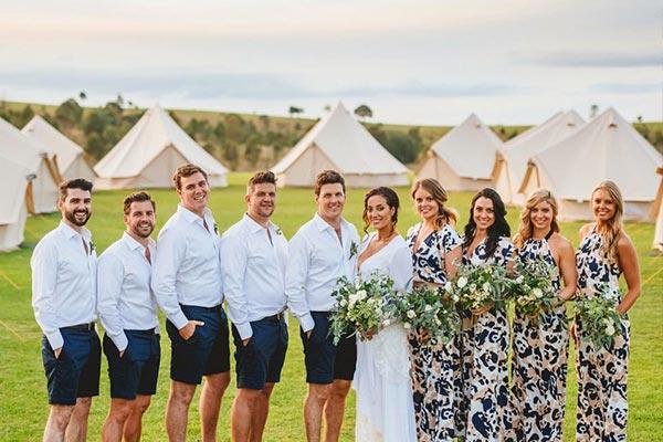 bell tent village behind wedding party