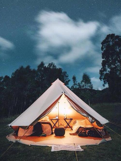 Bell tent with luxury package setup lit up under a starry sky