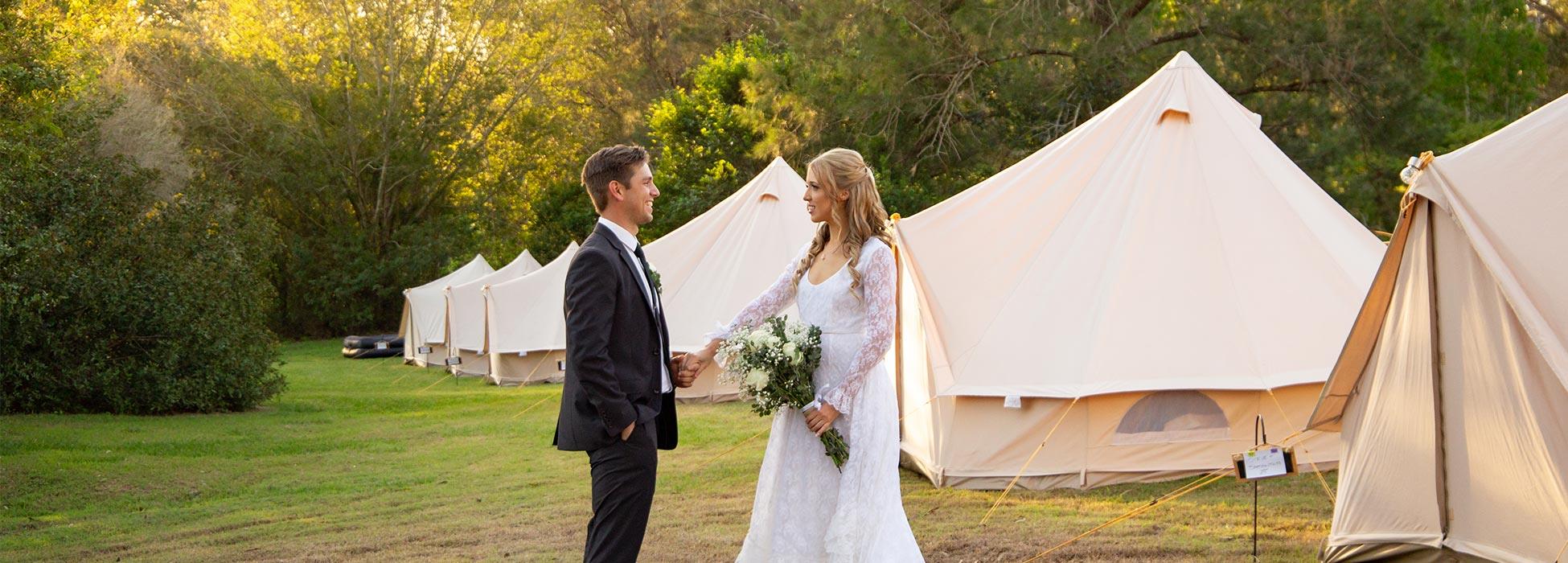 couple getting married with bell tents in background